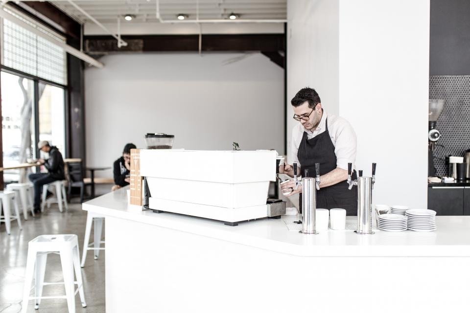 El dueño de un café trabajando detrás del mostrador de su local